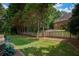The expansive backyard features a manicured lawn, mature trees, and a privacy fence, creating a serene outdoor oasis at 9975 Groomsbridge Rd, Johns Creek, GA 30022