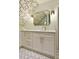 Charming bathroom with white vanity featuring gold hardware and a decorative mirror set against a lovely floral wallpaper at 9975 Groomsbridge Rd, Johns Creek, GA 30022