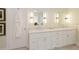Bright bathroom featuring a double vanity with white cabinets, marble countertop, and two decorative mirrors with modern lighting at 9975 Groomsbridge Rd, Johns Creek, GA 30022