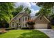 Charming home with a well manicured lawn, colorful shrubbery, and a two-car attached garage at 9975 Groomsbridge Rd, Johns Creek, GA 30022