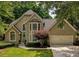 Charming home with a well manicured lawn, colorful shrubbery, and a two-car attached garage at 9975 Groomsbridge Rd, Johns Creek, GA 30022