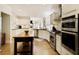 Open kitchen featuring white cabinets, black countertops, a kitchen island, and stainless steel appliances at 9975 Groomsbridge Rd, Johns Creek, GA 30022
