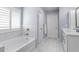 A soaking tub with marble-like tile surround with glass shower doors, white trim, and white cabinets at 244 Citrine Way, Acworth, GA 30101