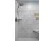 Close-up of a shower with a built-in bench, marble-like tile, and gold-colored fixtures at 244 Citrine Way, Acworth, GA 30101