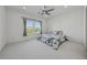Bright and airy bedroom featuring neutral carpet, a ceiling fan, and a large window overlooking a serene landscape at 7420 Wild Violet Dr, Cumming, GA 30040