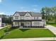 Wide-angle aerial view of landscaped lawn, long driveway, 2-car garage and black trimmed windows at 7420 Wild Violet Dr, Cumming, GA 30040