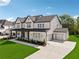New home with a spacious driveway, two-car garage, manicured lawn and black trimmed windows at 7420 Wild Violet Dr, Cumming, GA 30040