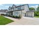 New two-story home featuring a long driveway, lush lawn, black trim, and separate two-car garage at 7420 Wild Violet Dr, Cumming, GA 30040