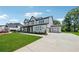 Lush green yard and long driveway lead to a new construction home with black trim and separate two-car garage at 7420 Wild Violet Dr, Cumming, GA 30040