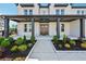 Inviting front porch with black trim, columns and decorative landscaping leading to a paneled front door at 7420 Wild Violet Dr, Cumming, GA 30040
