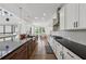 Bright kitchen featuring white cabinets, dark countertops, stainless steel appliances, and modern pendant lighting above the island at 7420 Wild Violet Dr, Cumming, GA 30040