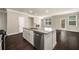 Open-concept kitchen with island, stainless steel appliances, and hardwood floors leading to the living area at 2629 Irwell Way, Lawrenceville, GA 30044
