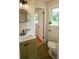 Bathroom with olive green vanity, modern faucet, and round mirror creates a stylish and functional space at 5254 Corinth Dr, Stone Mountain, GA 30087