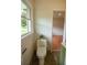 Bathroom featuring a toilet, and view through door to a room with wood floors and window with tree views at 5254 Corinth Dr, Stone Mountain, GA 30087
