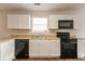 Well-lit kitchen featuring white cabinets and black appliances, creating a clean and modern look at 6528 Carriage Ln, Stone Mountain, GA 30087