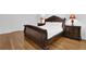 Elegant bedroom featuring hardwood floors, a detailed wood bed frame, and matching bedside tables with lamps at 7027 Walham Grv, Duluth, GA 30097