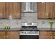 Close-up of the kitchen featuring stainless steel appliances, wood cabinetry and tile backsplash, offering a blend of style and function at 7027 Walham Grv, Duluth, GA 30097