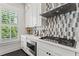 White kitchen featuring modern appliances, backsplash detail, and a view to the outside at 205 Maplewood Dr, Roswell, GA 30075