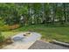 A lush backyard featuring a stone fire pit, a manicured lawn, and a wooded border for added privacy at 4363 Old Mabry Road Northeast Ne Rd, Roswell, GA 30075