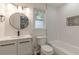 Bathroom with white tiling, round mirror, and white single sink vanity with drawers and cabinets at 3480 Tanbark Ne Ct, Brookhaven, GA 30319