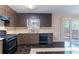 Cozy kitchen features dark cabinets, a window above the sink, and a black gas range at 6708 Bedford Rd, Rex, GA 30273