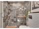 Tiled walk-in shower with glass door, built-in shelving, and sleek gray tiling at 943 Peachtree Ne St # 814, Atlanta, GA 30309