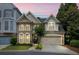 Charming brick home featuring a two-car garage, manicured lawn, and beautiful landscaping during sunset at 200 Mystic Ct, Atlanta, GA 30342