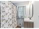 Cozy bathroom with a single sink vanity, modern oval mirror, and shower with leaf-patterned curtain at 1326 Stella Sw Cir, Mableton, GA 30126