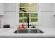 Kitchen sink, faucet, and window overlook a green view with white subway tile and quartz countertops at 1326 Stella Sw Cir, Mableton, GA 30126