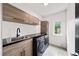 Modern laundry room featuring stylish cabinetry, a sink, a front loading washer and dryer, and a window at 2220 Meadowvale Ne Dr, Atlanta, GA 30345