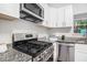 Close-up of a modern kitchen with granite countertops and stainless steel appliances and white cabinets at 3440 Oaktree Way, Stonecrest, GA 30038