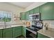 Green cabinets, stainless steel appliances, and granite countertops are features of this bright kitchen at 2084 Del Lago Nw Cir # 1, Kennesaw, GA 30152