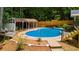 Backyard pool features a diving board and covered patio seating surrounded by beautiful landscaping and mature trees at 1035 Hunterhill Dr, Roswell, GA 30075