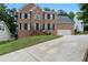 Traditional two-story brick home with a manicured lawn and a long driveway leading to a two-car garage at 2167 Merrymount Dr, Suwanee, GA 30024