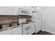 Well-lit kitchen with white cabinets and appliances, and easy access to the sink and cooking range at 2167 Merrymount Dr, Suwanee, GA 30024