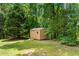 Backyard view of a wooden storage shed with a ramp in a lush, green landscape setting at 6020 Cochran Mill Rd, Palmetto, GA 30268