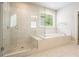 Bathroom showcasing a walk-in glass shower and soaking tub with tile surround and a window at 622 Denali Dr, Mableton, GA 30126