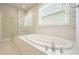 Bright bathroom featuring a soaking tub with tile surround and a glass-enclosed shower at 622 Denali Dr, Mableton, GA 30126