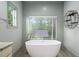 Bright bathroom featuring a standalone tub with a view to the outdoors through a large window at 3561 Stone Dr, Marietta, GA 30062