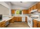 Well-lit kitchen featuring wood cabinets, white appliances, and a window overlooking the backyard at 2109 Tranquility Ct, Woodstock, GA 30188