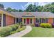 Lovely brick home with lush landscaping, dark shutters, and a welcoming front entrance with a red door at 3550 Miller Farms Ln, Peachtree Corners, GA 30096