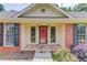 Close-up of a charming porch with a stone walkway, red door, and dark shutters, framed by brick at 3550 Miller Farms Ln, Peachtree Corners, GA 30096