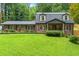 Charming brick home with a well-manicured lawn and lush greenery, showcasing classic architectural details at 1050 Lake Charles Dr, Roswell, GA 30075