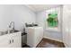 Bright laundry room with a sink, washer, dryer, cabinet space and a window offering a view of the outdoors at 1050 Lake Charles Dr, Roswell, GA 30075