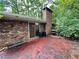 View of a vintage-looking patio with a brick chimney and worn surface surrounded by mature trees and foliage at 1333 Council Bluff Ne Dr, Atlanta, GA 30345