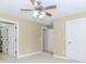 Large bedroom with neutral walls, plush carpeting, ceiling fan, and multiple doors providing easy access at 2727 Bearcreek Pl, Buford, GA 30519