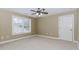 Spacious bedroom with neutral walls, plush carpeting, ceiling fan, and large window letting in natural light at 2727 Bearcreek Pl, Buford, GA 30519