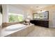 Bright bathroom with a soaking tub, dark cabinets, and neutral tile flooring at 6110 Read Rd, Suwanee, GA 30024