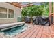 Hot tub on wood deck with an open pergola featuring an outdoor grill, and view of the wooded surroundings at 3605 Hickory Se Cir, Smyrna, GA 30080