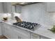 Close up of stainless steel cooktop and white and gold backsplash on marble countertop at 3899 Carlton Dr, Chamblee, GA 30341